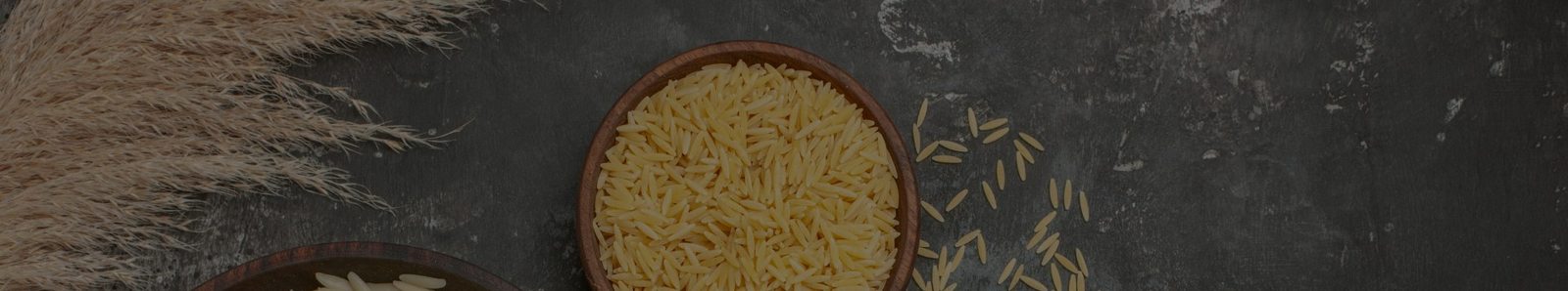 Bowls of cooked and raw Basmati rice on a dark surface